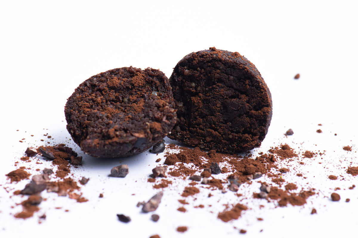 Two chocolate truffles with cocoa powder on a white background