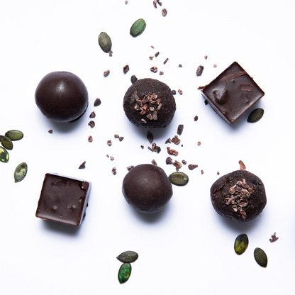 Dark chocolate truffles with pumpkin seeds and cacao nibs on a white background