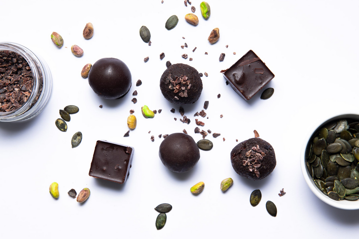 Dark chocolate truffles with pumpkin seeds and cacao nibs on a white background